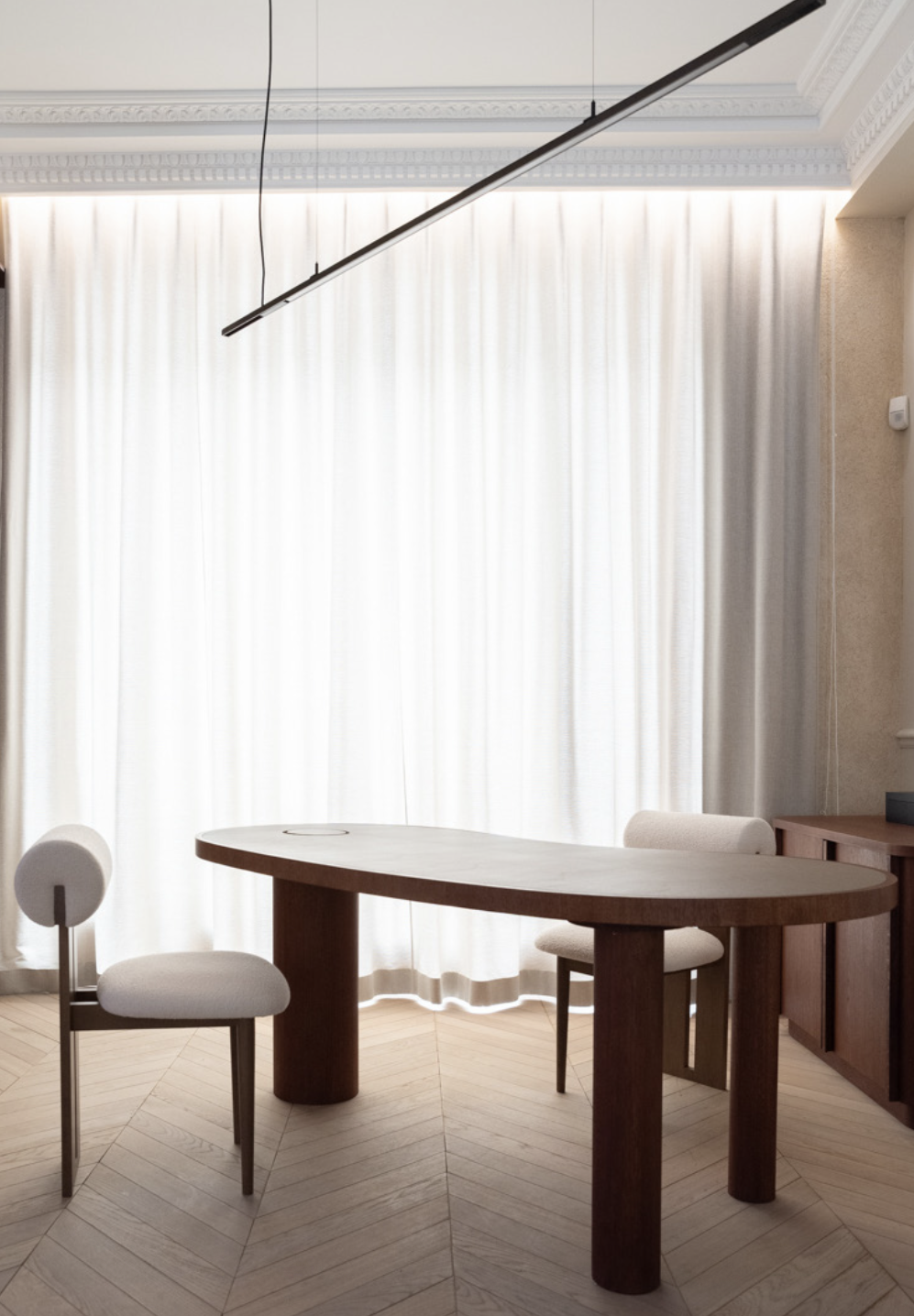 Bureau privé — table ovale noyer, chaise bouclette, suspension linéaire
