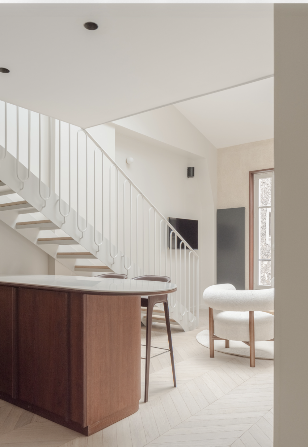 Cuisine — îlot noyer marbre, escalier blanc, tabourets cuir